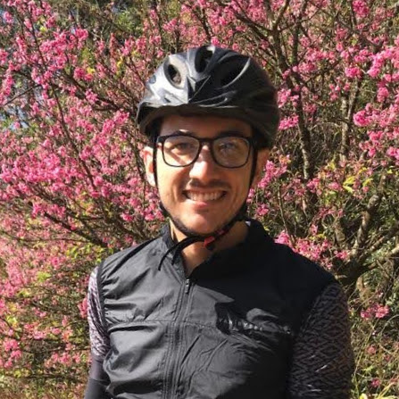 fernando cintra.cc professional cycling writer with helmet and pink flower tree in the background